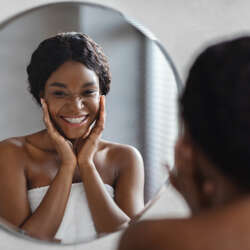 Mirror reflection of young black woman smiling
